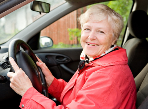 Older lady smiling and driving a car 